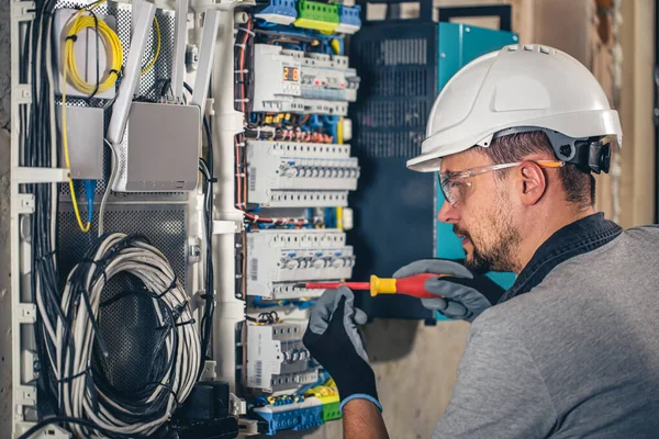 Man, an electrical technician working in a switchboard with fuses. Installation and connection of electrical equipment.