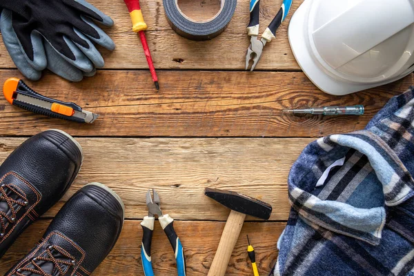 Flat lay composition with tools and work uniform on wooden background, space for text.