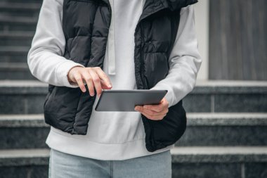 Kapatın, kadın tablet kullanıyor, şehir arka planı bulanık, vücut parçası.