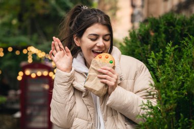 Güzel bir zencefilli ekmeği olan çekici genç bir kadın bulanık bir arka planda yürüyüşte..