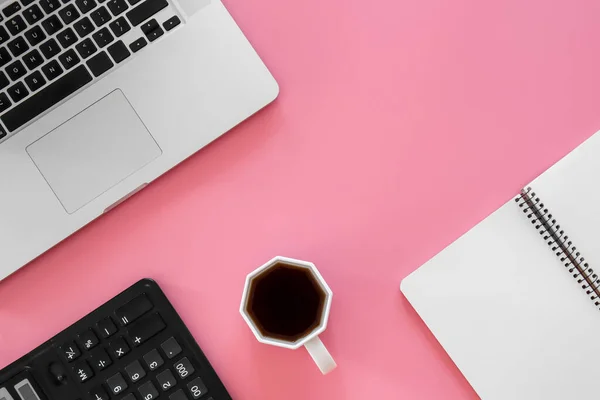 Office background with coffee, laptop on a pink background, conceptual minimalism, copy space.