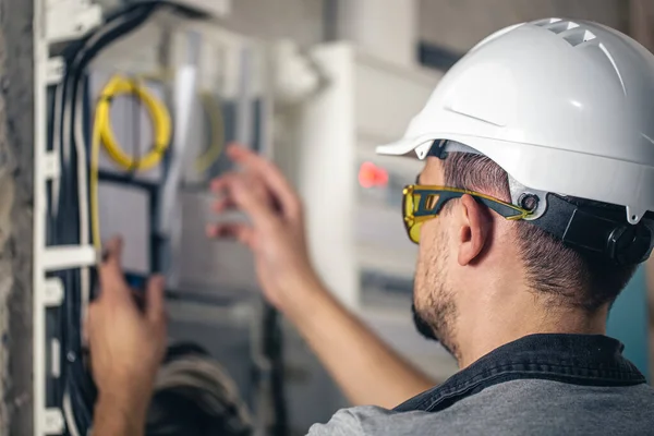 Man, an electrical technician working in a switchboard with fuses. Installation and connection of electrical equipment.