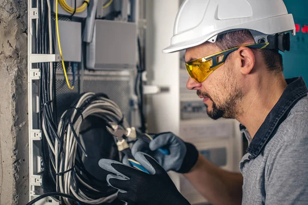 Man, an electrical technician working in a switchboard with fuses. Installation and connection of electrical equipment.