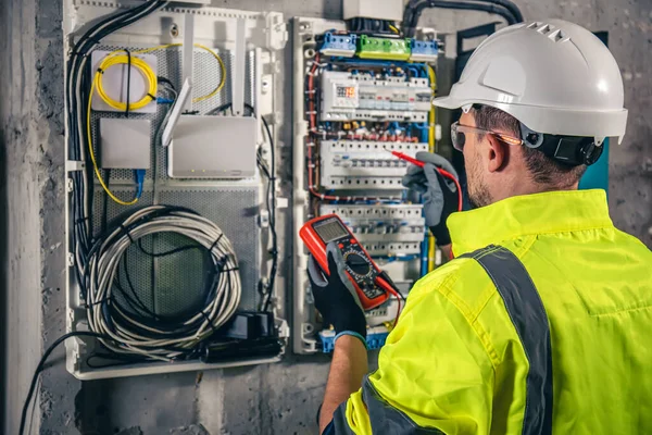 Man, an electrical technician working in a switchboard with fuses. Installation and connection of electrical equipment.