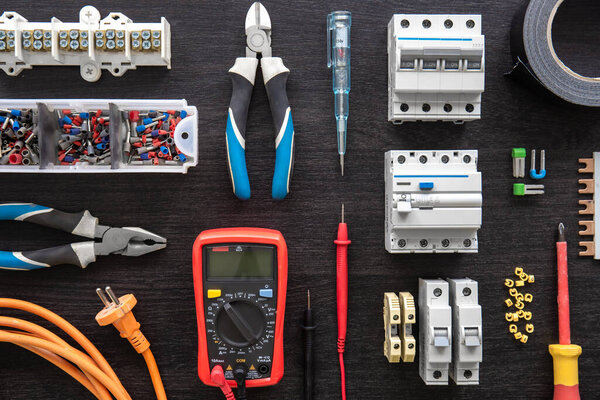 Flat lay composition with electrical tools on wooden background.