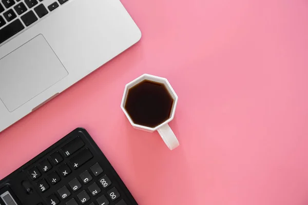 Office background with coffee, laptop on a pink background, conceptual minimalism, copy space.