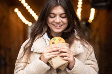 Elinde zencefilli çörekle çekici bir genç kadın, bir kadının ellerinde güzel bir zencefilli çörek, bir şehir yürüyüşü..