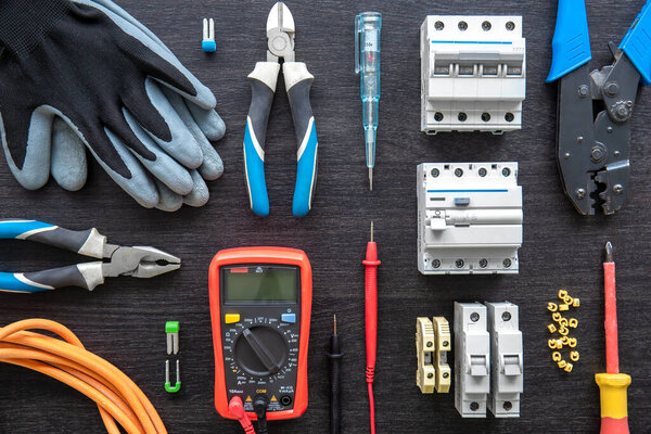 Flat lay composition with electrical tools on wooden background.
