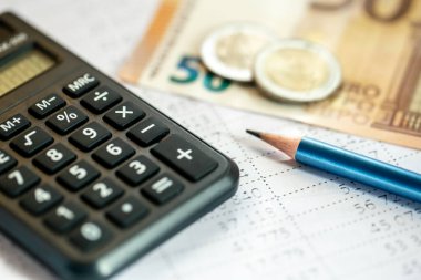 Bulanık bir arkaplanda hesap makinesi, para ve kalem yakın plan, vergi hesapları ve finans kavramı.