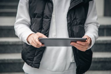Kapatın, kadın tablet kullanıyor, şehir arka planı bulanık, vücut parçası.