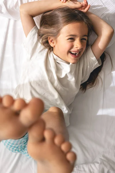 Ένα Χαριτωμένο Κοριτσάκι Ξαπλώνει Στο Κρεβάτι Πρωί Και Χαμογελάει Θέα — Φωτογραφία Αρχείου