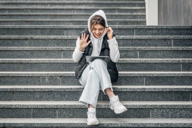 Genç bir kız öğrenci elinde dijital tabletle basamaklarda oturuyor, teknoloji ve eğitim kavramı, kopyalama alanı.