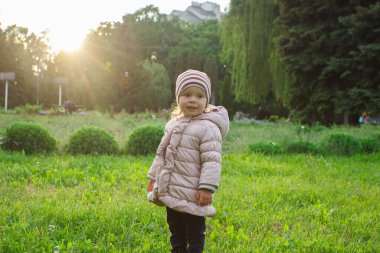 Parktaki küçük tatlı kız, yumuşak odaklı arka plan.