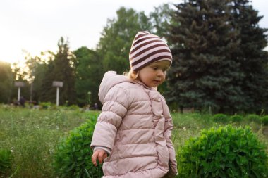 Parktaki küçük tatlı kız, yumuşak odaklı arka plan.