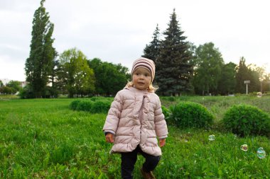 Parktaki küçük tatlı kız, yumuşak odaklı arka plan.