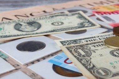 Bir büyüteçle farklı koleksiyoncu paraları ve banknotların arka planı, üst görünüm