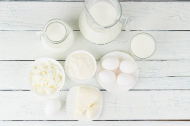 Beyaz tahta tahtalarda farklı süt ürünleri, bulanık arka plan.