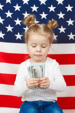 Amerikan Dollarsi 'si olan küçük güzel bir kız elleri, arka planda Amerikan Bayrağı