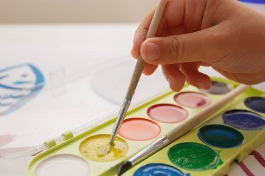 Child drawing a picture by watercolor, back to school concept
