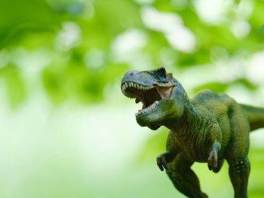 Tyrannosaurus figürü ve yeşil orman