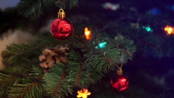 Close-up Garlands of light bulbs with toy glass balls are flashing on the artificial Christmas tree. High-quality frames in 4k format. holiday concept, christmas eve, new year, magic, christmas spirit — Vídeo de Stock