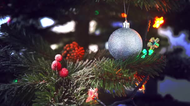 Feliz Año Nuevo árbol de Navidad decora con bola de cristal de plata en la nieve rama en el fondo bokeh de lado parpadeo bombillas guirnaldas para vacaciones familiares. Concepto - humor del festival, emoción positiva — Vídeo de stock