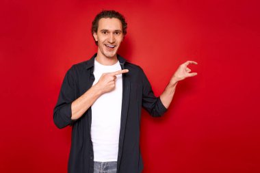 Mutlu Avrupalı genç bir adamın küçük bir el hareketi yaparak küçük bir nesne ölçümlemesi, yüzünde gülümseme, günlük kıyafetler, koyu mavi gömlek, küçük bir şey gösteriyor.