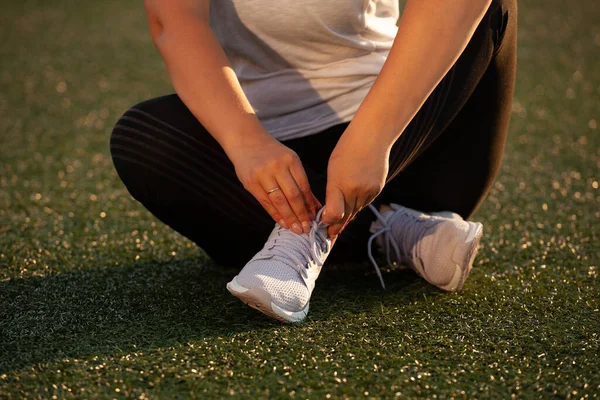 Chica atlética atando los cordones de las zapatillas en el estadio — Foto de Stock