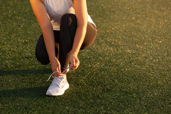 Stadyumda spor ayakkabısının bağcıklarını bağlayan atletik kız — Stok fotoğraf
