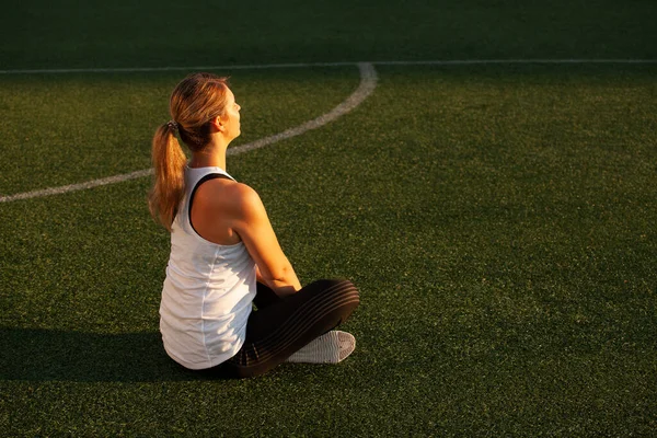 Chica deportiva haciendo yoga en el césped del estadio — Foto de Stock