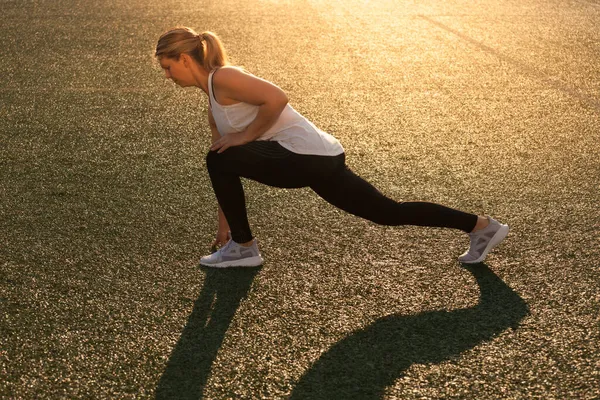 Chica de deportes haciendo estiramiento en el césped del estadio — Foto de Stock