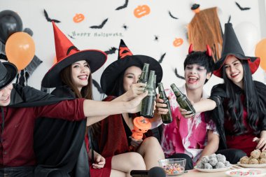 Genç Asyalı kostümlü cadı çetesi Cadılar Bayramı partisini kutlayan ve odada içki içen büyücü. Gençler ve Taylandlılar Cadılar Bayramı 'nı kutluyor. Kavram partisi Cadılar Bayramı evde.