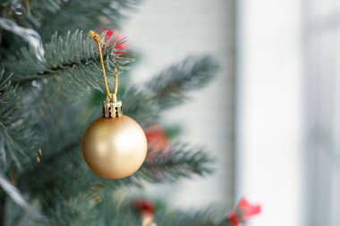 Madalyalı bir Noel ağacında asılı duran altın kürenin yakın çekimi. Noel ve Yeni Yıl tatilleri.