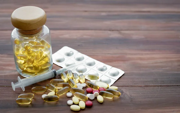 Ahşap arka planda tıp konsepti. Tıp alanında tıp kavramı. Haplar, diyet takviyeleri bir araya toplanmış..