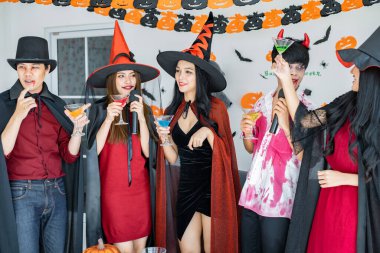 Kostüm giymiş genç Asyalı cadı çetesi, Cadılar Bayramı partisini kutlayan büyücü odada şarkı söyleyip içki içen büyücü. Gençler ve Taylandlılar Cadılar Bayramı 'nı kutluyor. Kavram partisi Cadılar Bayramı evde.