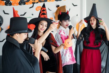 Kostüm giymiş genç Asyalı cadı çetesi, Cadılar Bayramı partisini kutlayan büyücü odada şarkı söyleyip içki içen büyücü. Gençler ve Taylandlılar Cadılar Bayramı 'nı kutluyor. Kavram partisi Cadılar Bayramı evde.