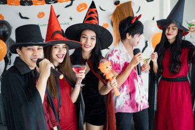 Kostüm giymiş genç Asyalı cadı çetesi, Cadılar Bayramı partisini kutlayan büyücü odada şarkı söyleyip içki içen büyücü. Gençler ve Taylandlılar Cadılar Bayramı 'nı kutluyor. Kavram partisi Cadılar Bayramı evde.