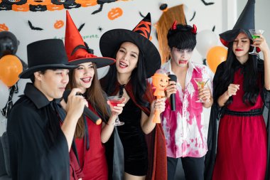 Kostüm giymiş genç Asyalı cadı çetesi, Cadılar Bayramı partisini kutlayan büyücü odada şarkı söyleyip içki içen büyücü. Gençler ve Taylandlılar Cadılar Bayramı 'nı kutluyor. Kavram partisi Cadılar Bayramı evde.