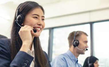 Güzel Asyalı kadın ve çeşitli tele pazarlama müşteri hizmetleri ekibi çağrı merkezinde. Ekip eşliğinde çağrı merkezi çalışanı. İş yerindeki müşteri destek operatörünün gülümsemesi.