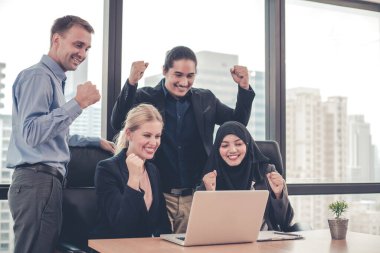 Bir grup ofis çalışanı dizüstü bilgisayarlarında bir gülümsemeyle ve arka planda şehir binalarıyla birlikte başarılı bir şekilde çalışıyorlar. Ofis çalışanları grubunda başarılı olduğuna sevindim..