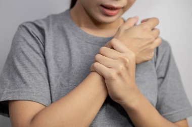 Bilek ağrısı çeken bir kadın. Kadın bileğinde ağrı. Acı dolu bileğini arka planda tutan genç bir kadın..