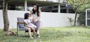 Asyalı anne ve kızı bahçede eğlenceli aktiviteler yapıyor. Anne ve kızı birlikte oynuyorlar. Mutlu sevgi dolu aile kavramı.