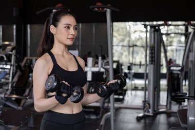 Salonda fotokopi odalı halterli Asyalı seksi kadınlar egzersizi. Dambılı kaldıran tatlı bir kadın. Jimnastik arka planında dambılı tutan Taylandlı kız. Spor salonundaki egzersiz kavramı.