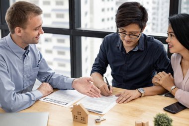Couple signed the house purchase contract with the house sales agents. Buy or sell home concept.