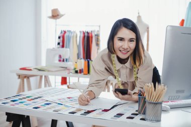 Designer are thinking and designing clothes for customers order items at the designer desk in the studio. Clothes designers are working in the office.
