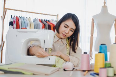 Professional fashion designers are cutting new clothes using sewing machines in studio. Designer using sewing machine in working. Startup designer concept.
