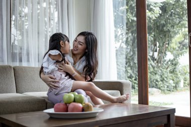 Asyalı anne ve kızı resepsiyon odasında eğlenceli aktiviteler yapıyor. Anne ve kızı birlikte oynuyorlar. Mutlu sevgi dolu aile kavramı.