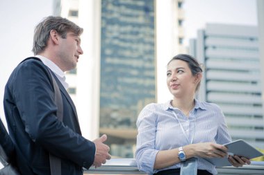 Professional discussion of businessman and businesswoman at outside office building with background the city. Business people with exchange ideas with each other.