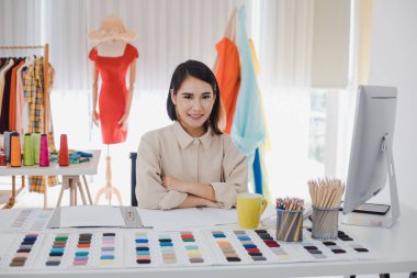 Portrait of Asian designer clothes woman at work table in the office with success business. Startup designer concept. Clothes designers are working in studio.