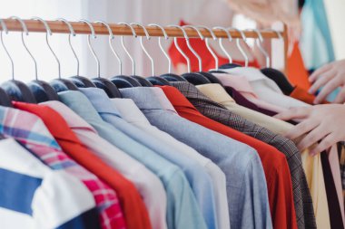 Çamaşır ipinden gömlek seçen müşteriler. Çeşitlilik ve modern moda kıyafetleri, çamaşır ipine asılmış düzen. Tasarımcı giyim mağazasında giysiler rafta asılı. Moda eğilimi konsepti.